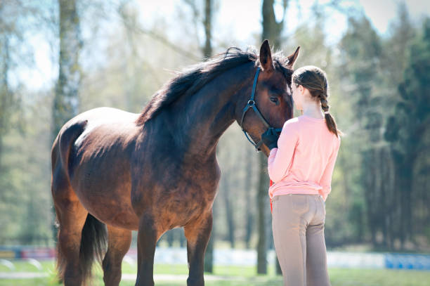 Young teenage girl standing with her favorite brown horse. Colored outdoors horizontal springtime image. Light vintage filter.