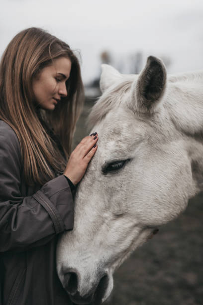 Girl stand with horse on the field, grey tones